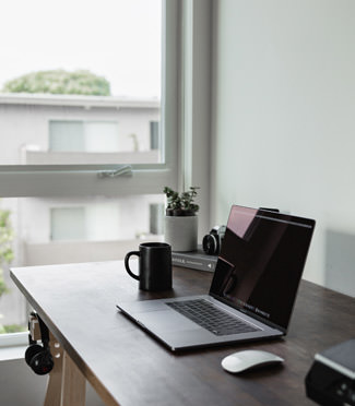 Computer on desk by an open window