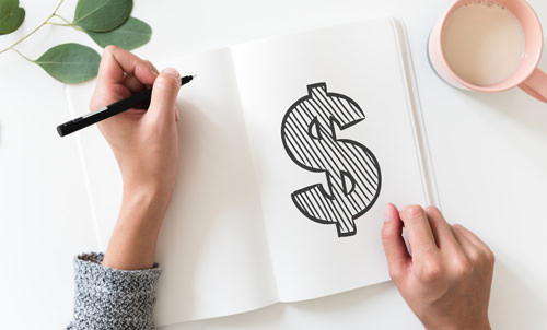 Hands drawing dollar sign in notebook